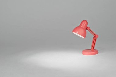 Kağıtların arka planında pembe lamba. Oyuncak masa lambası. Lambanın yanındaki metin için boşluk ve boşluk kopyala. Oda ve yaratıcı fikirler kavramı..