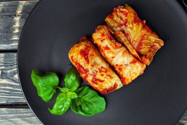 Kara tabakta lahana ve pirinç ile lahana ruloları. Eski ahşap bir masada yemek. Karanlık bir arka planda doldurulmuş lahana..