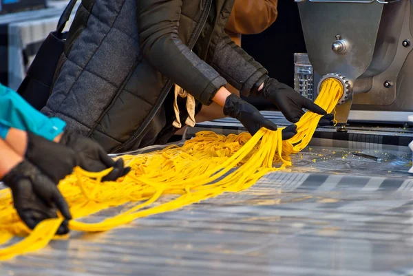 フェアでのスパゲティ生産のデモンストレーション 世界で最も長いパスタのレコードを設定します 黄色の長いパスタは ニンニクプレスから出てくる — ストック写真