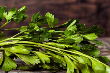 Siyah ahşap bir masada maydanoz. Maydanoz sürüsü koyu bir arkaplanda. Eski püskü bir kalbe yeşiller.
