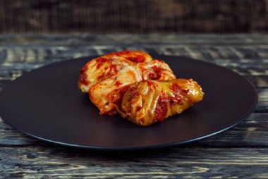 Kara tabakta lahana ve pirinç ile lahana ruloları. Eski ahşap bir masada yemek. Karanlık bir arka planda doldurulmuş lahana..