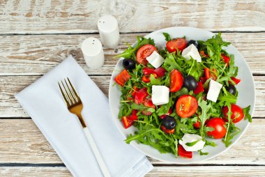 Beyaz kasede Yunan salatası. Beyaz arka planda taze sebze salatası. Sehpada yemek. Eski ahşap bir tahtada kase.