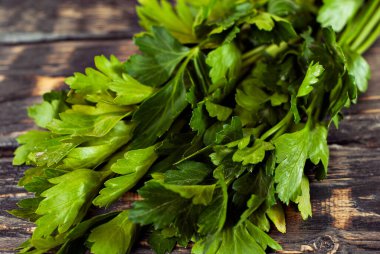 Siyah ahşap bir masada maydanoz. Maydanoz sürüsü koyu bir arkaplanda. Eski püskü bir kalbe yeşiller.