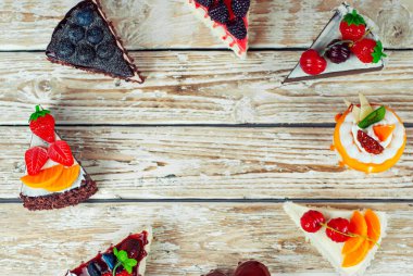 Beyaz arka planda farklı pastalar. Çikolatalı ve meyveli kek parçaları. Pejmürde bir masa üzerindeki şekerler.