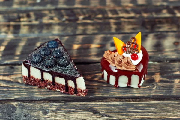 两块白色的蛋糕 背景是黑色的巧克力奶油 用蓝莓和水果在木制桌子上做的蛋糕 — 图库照片
