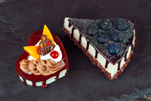 两块白色的蛋糕 背景是黑色的巧克力奶油 蓝莓和水果在石板上的蛋糕 — 图库照片