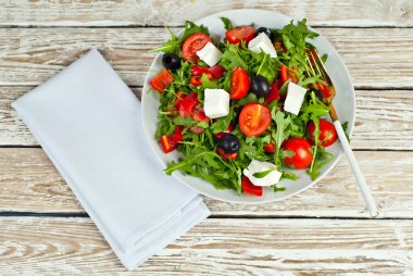 Beyaz kasede Yunan salatası. Beyaz arka planda taze sebze salatası. Sehpada yemek. Eski ahşap bir tahtada kase.