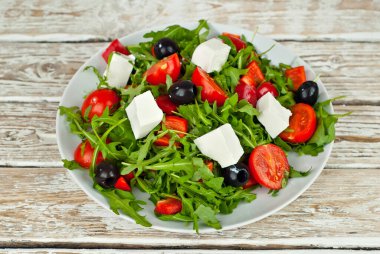 Beyaz kasede Yunan salatası. Beyaz arka planda taze sebze salatası. Sehpada yemek. Eski ahşap bir tahtada kase.