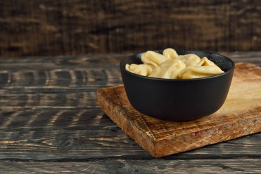 Siyah bir kasedeki askerler. Siyah arka planda hamur ve patates tabakları. Tahta bir masada Ukrayna ulusal yemeği. Yemek yakınındaki metin için boşluk ve boş alanı kopyala.