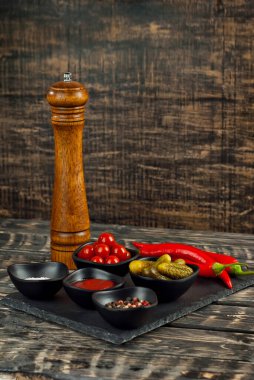 Kesme tahtasındaki nane ve baharatlar. Eski püskü bir masada salatalık, domates, sos, tuz, biber ve baharat turşusu..