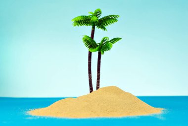 Cennet adasında minyatür palmiye ağaçları. Kumsalın manzarası, kumsalda palmiye ağaçları var. Arka planda mavi gökyüzü. Dinlenme ve seyahat konsepti.