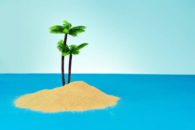 Cennet adasında minyatür palmiye ağaçları. Kumsalın manzarası, kumsalda palmiye ağaçları var. Arka planda mavi gökyüzü. Dinlenme ve seyahat konsepti.