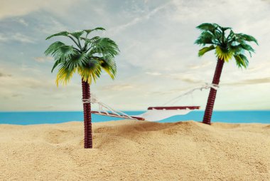 Yapay palmiye ağaçlarında minyatür hamak. Kumsalın manzarası, kumsalda palmiye ağaçları var. Arka planda mavi gökyüzü. Dinlenme ve seyahat konsepti.
