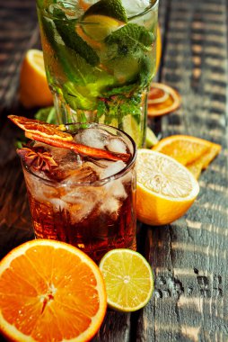 Siyah arka planda pipetli, buzlu ve meyveli kokteyller. Eski ahşap bir masada alkollü içecekler. Yakın plan. Sefil kahverengi bir tahtanın üzerinde iç..