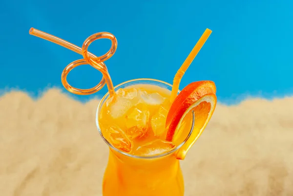 ビーチでオレンジカクテル 氷とアルコール飲料 砂の上にオレンジを閉じる — ストック写真