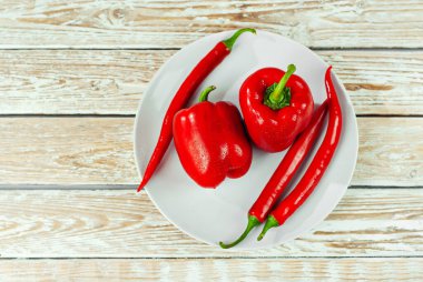 Beyaz arka planda biberler ve domatesler. Kapalı tabakta kırmızı sebzeler. Eski püskü bir tahtada acı biber ve domates. Yemek yakınındaki metin için boşluk ve boş alanı kopyala.