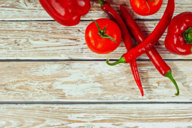 Beyaz arka planda biberler ve domatesler. Kırmızı sebzeler yakın. Eski püskü bir tahtada acı biber ve domates. Yemek yakınındaki metin için boşluk ve boş alanı kopyala.