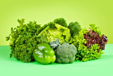 Lahana, biber, maydanoz, dereotu, marul, yeşil arka planda brokoli. Yığınla sebze..