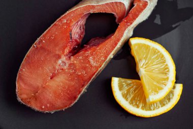 Siyah tabakta çiğ somon bifteği. Limonlu kırmızı somon. Yaklaş..