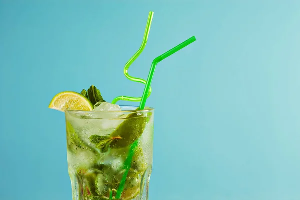 Zielony Koktajl Słomkami Niebieskim Tle Alkoholowe Mojito Lodem Limonką Miętą — Zdjęcie stockowe