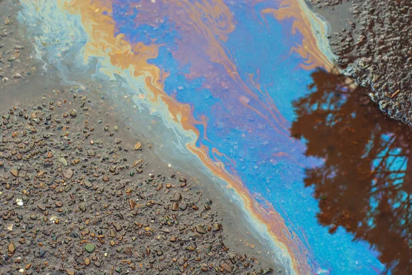 湿沥青上有油渍 桶被五颜六色的油流污染了 环境污染 石油外溢和环境问题的概念 — 图库照片