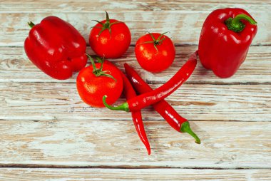 Beyaz arka planda biberler ve domatesler. Kırmızı sebzeler yakın. Eski püskü bir tahtada acı biber ve domates. 