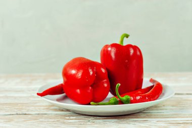 Beyaz arka planda biberler ve domatesler. Kapalı tabakta kırmızı sebzeler. Eski püskü bir tahtada acı biber ve domates. Yemek yakınındaki metin için boşluk ve boş alanı kopyala.