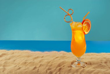 Plajda portakal kokteyli. Buzlu alkollü içecek, kumda portakal rengi..