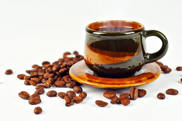 セラミックブラウンコーヒーマグカップを閉じます コーヒーは白い背景に隔離されている コーヒー豆は飲み物の近くに散らばっています — ストック写真