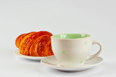 Tabakta sarı kruvasan ve beyaz arka planda izole edilmiş kahve. Klasik kahvaltı. Yakın çekim..