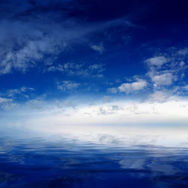Облачно-голубое небо выходит на горизонт над голубой поверхностью моря — стоковое фото