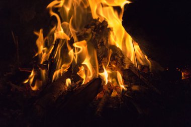 Gece karanlığında parlak alevlerin ve alevlerin manzarası.