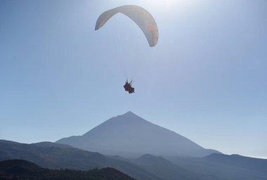 Arka planda Teide Dağı ile mavi gökyüzünde uçan paraglider. Tenerife, Kanarya Adaları, İspanya. 