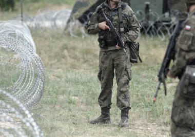 Sınırda Polonya askerleri var. Borddaki çitin yanında Polonyalı askerler var.