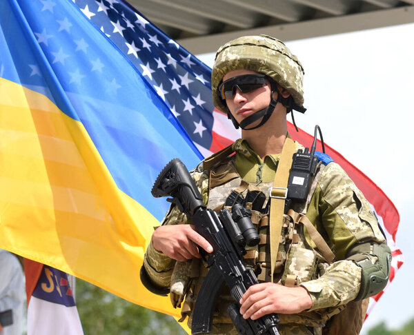 Yavoriv, Ukraine - July 27, 2021. Ukrainian soldier near  flags of Ukraine and US during the Three Swords 2021 multinational military exercise near Yavoriv in western Ukraine.