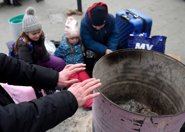 Lviv, Ukrayna - 8 Mart 2022: Mülteciler Ukrayna 'nın batısındaki Lviv tren istasyonunun dışında bir şenlik ateşi etrafında ısınıyorlar.