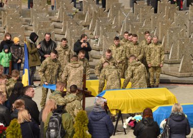 Lviv, Ukrayna - 29 Mart 2022: Askerler, Rusya 'nın Ukrayna' yı işgali sırasında Lviv kentindeki Lychakiv mezarlığında düzenlenen cenaze törenlerinde Ukrayna bayrağıyla öldürülen Ukraynalı askerlerin tabutlarını örttüler.
