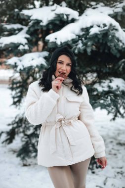 Kışın Noel ağacının yanında çikolata yiyen güzel bir kızın portresi. Mutlu kız çikolata yiyor..