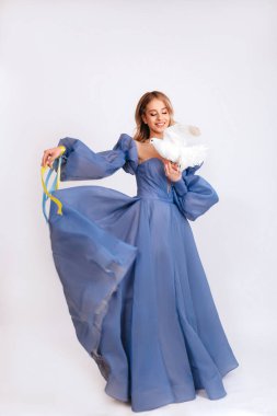 Ukrayna için dua et. Mavi kabarık elbiseli, Ukrayna bayrağı renginde kurdeleli genç bir kadın beyaz arka planda barışın beyaz güvercin sembolünü taşıyor. Savaşı durdurun. Boşluğu kopyala.