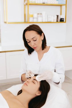 The beautician wipes the girl's face with cotton pads.