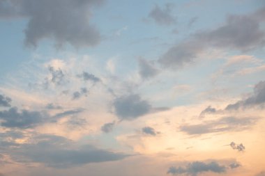 Blue sky with golden light and clouds at sunset.
