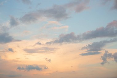 Blue sky with golden light and clouds at sunset.