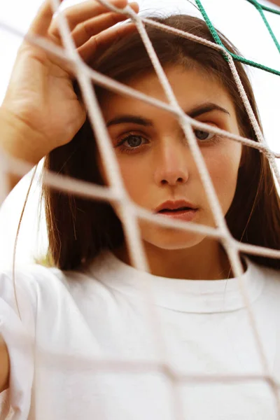 The girl looks through the football net. Girl\'s face close-up through the mesh.