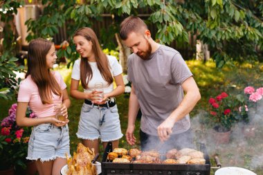 Family barbecue grill in the garden. Barbecue party. A family having fun and chatting on the grill. Man doing barbecue on the grill. 