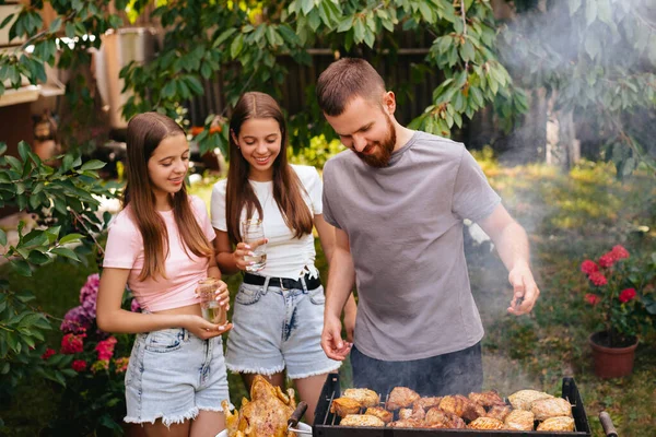 Family barbecue grill in the garden. Barbecue party. A family having fun and chatting on the grill. Man doing barbecue on the grill.