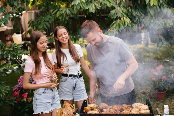 Family barbecue grill in the garden. Barbecue party. A family having fun and chatting on the grill. Man doing barbecue on the grill.