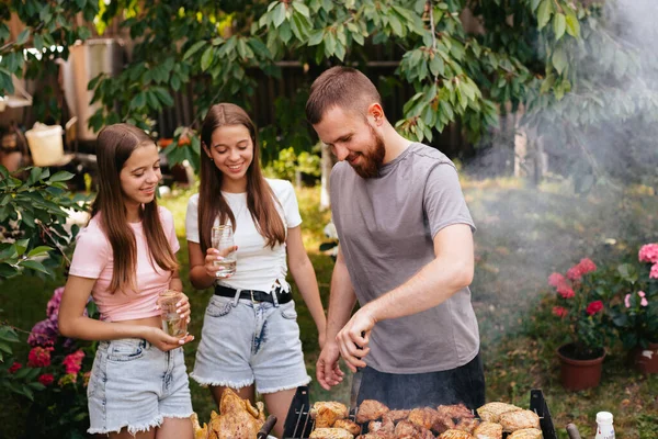 Family barbecue grill in the garden. Barbecue party. A family having fun and chatting on the grill. Man doing barbecue on the grill.