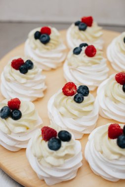 Tahta üzerinde ahududu ve yaban mersinli tatlı. Meyveli tatlı pavlova. 