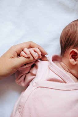 Bebek, annesinin parmağını elinde tutuyordu. Aile kavramı. Anne ve bebek. 