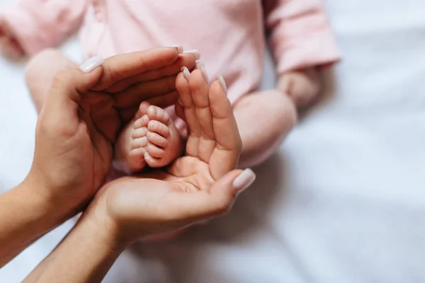 Annenin ellerinde, kalp şeklinde küçük bebek ayakları var. Aile kavramı. Anne ve bebek. 